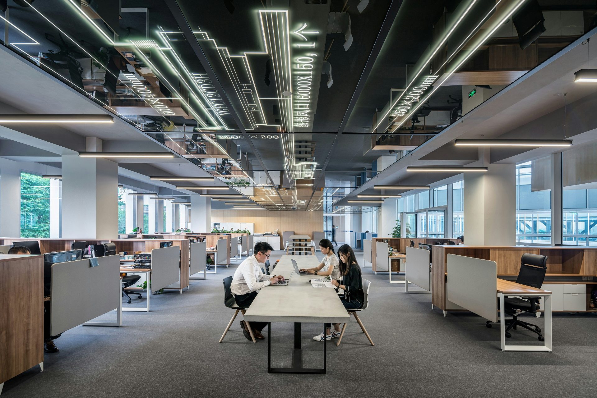 Trois personnes collaborant dans un bureau en espace ouvert.